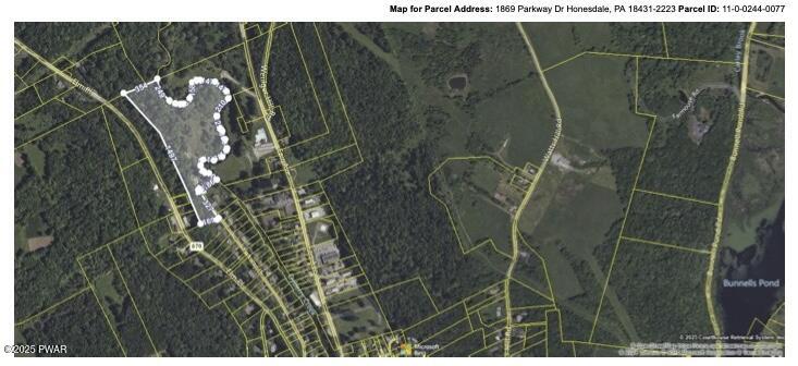 Aerial parcel map with outlined property boundaries and nearby roads/terrain.