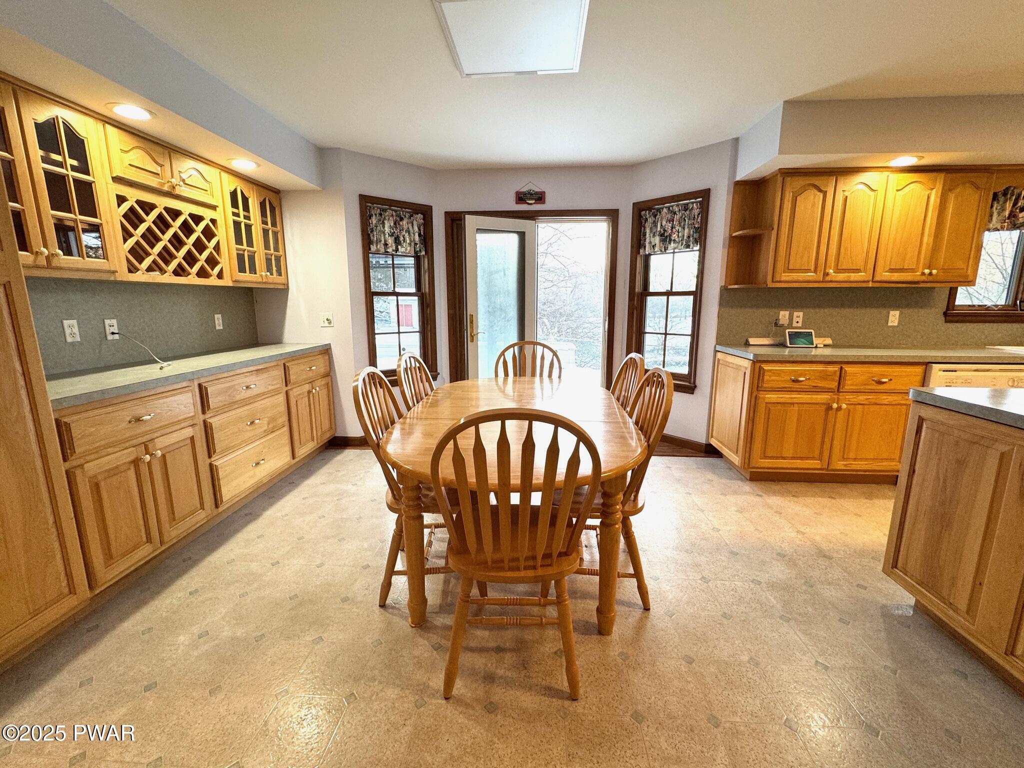 Spacious kitchen with wood cabinets, an oval dining table with chairs, and a door with windows at the back.