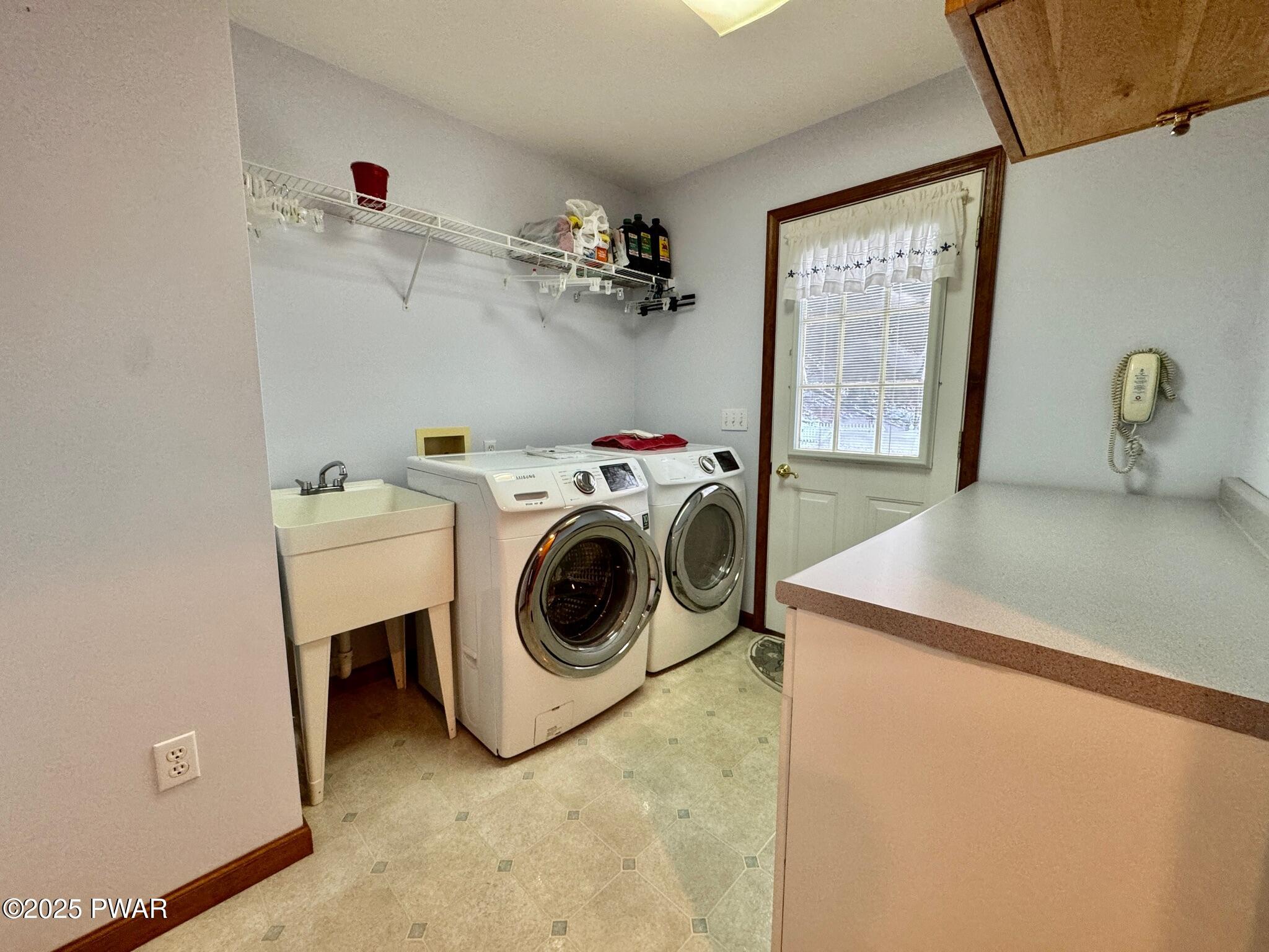 Laundry room with washer and dryer, utility sink, wire shelf, and a door with a window.