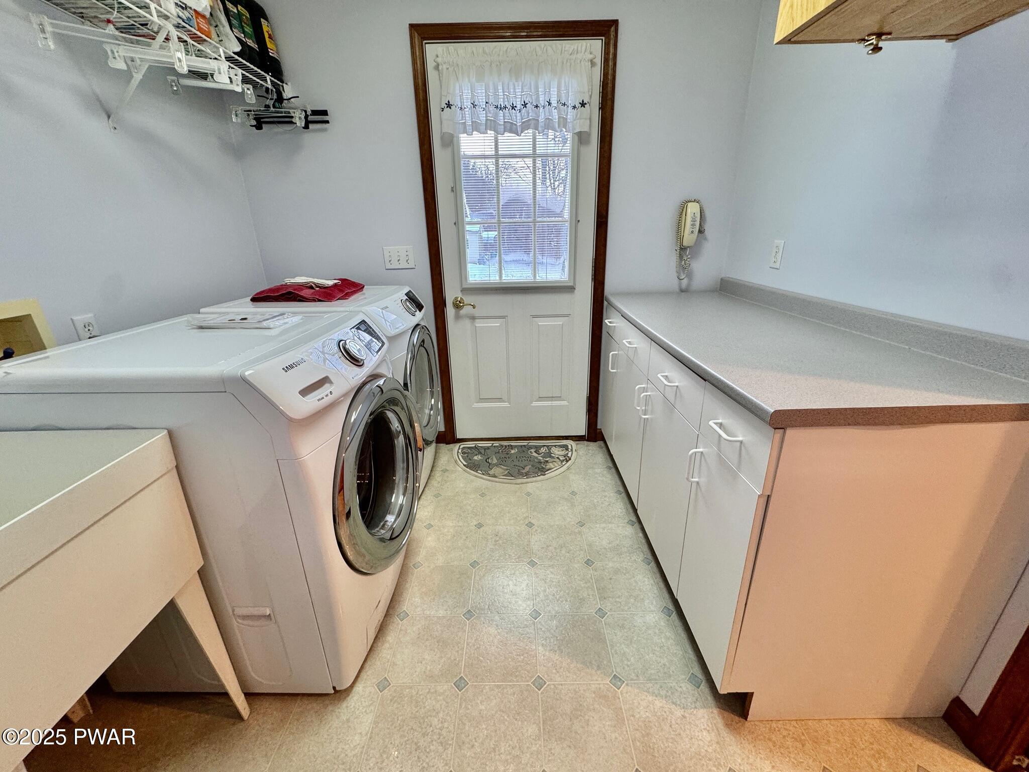 Laundry room with a washer and dryer on the left, countertop cabinets on the right, and a back door with a window at the end.