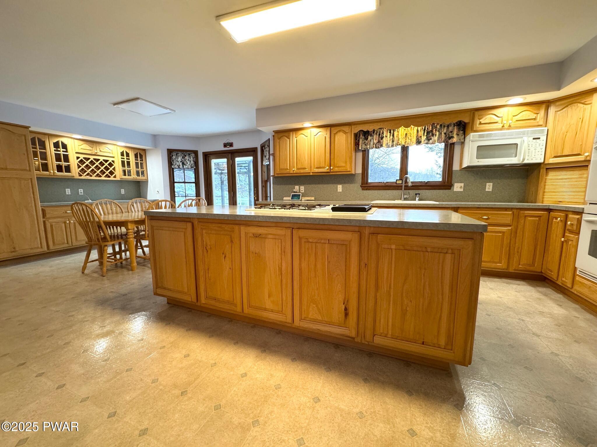 Spacious kitchen with a large center island, wood cabinets, dining nook, and built-in microwave.