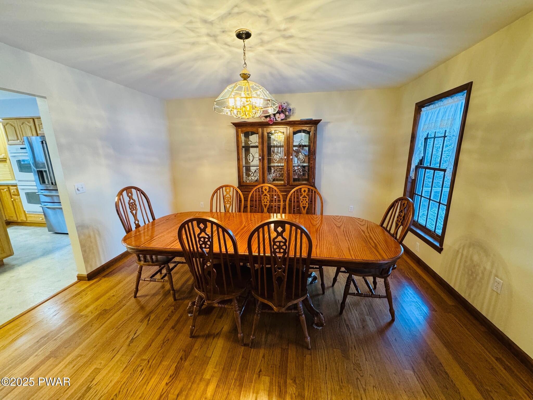 Dining room with wooden table and chairs, china cabinet, and chandelier.
