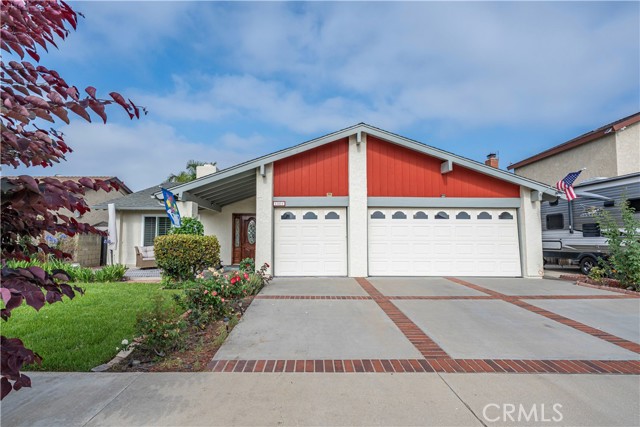 Single-story suburban home with red-and-white facade, two-car garage, brick-edged driveway, and landscaped front yard.