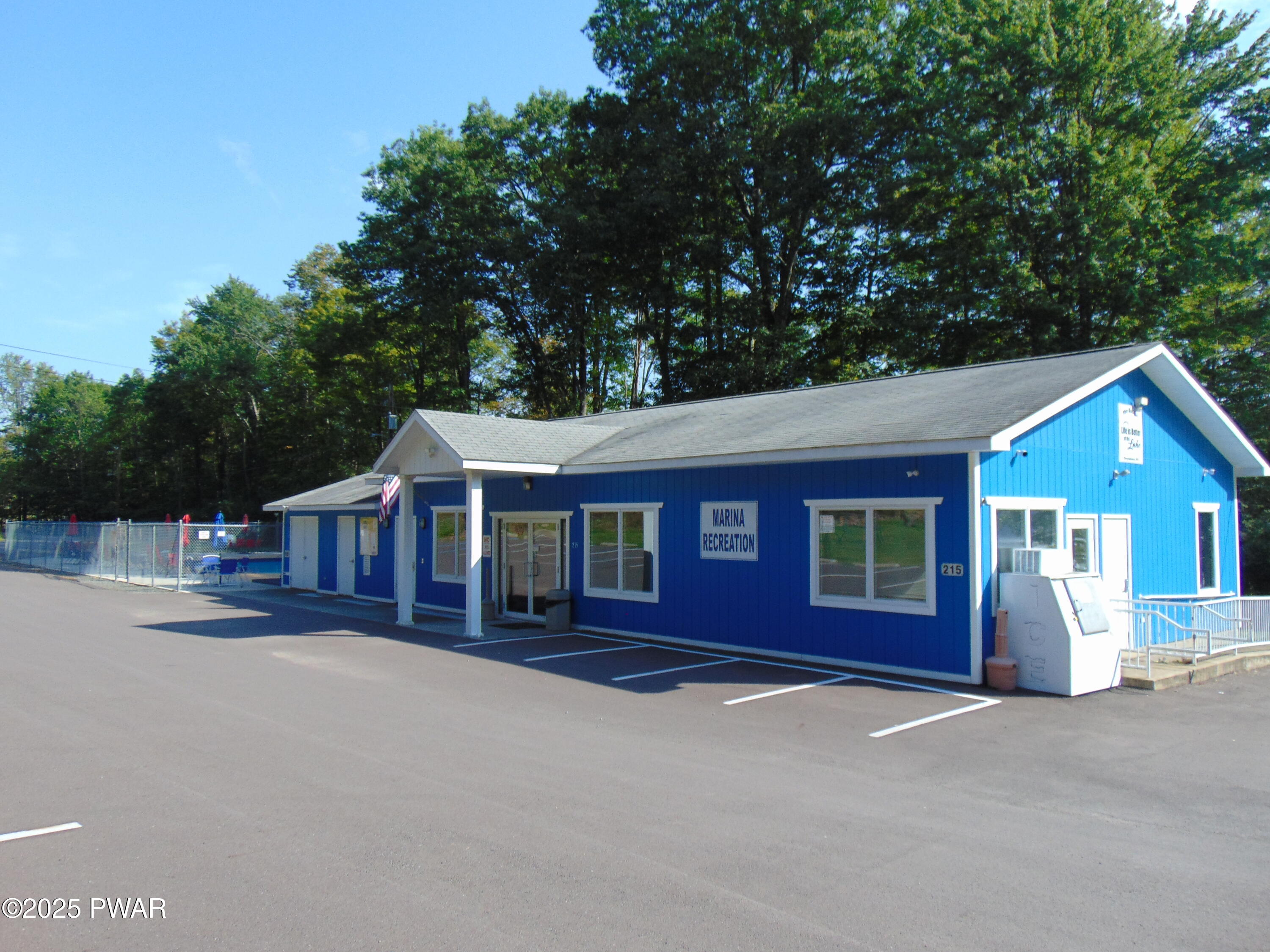 Blue single-story commercial building labeled Marina Recreation with parking spaces in front and trees behind it.