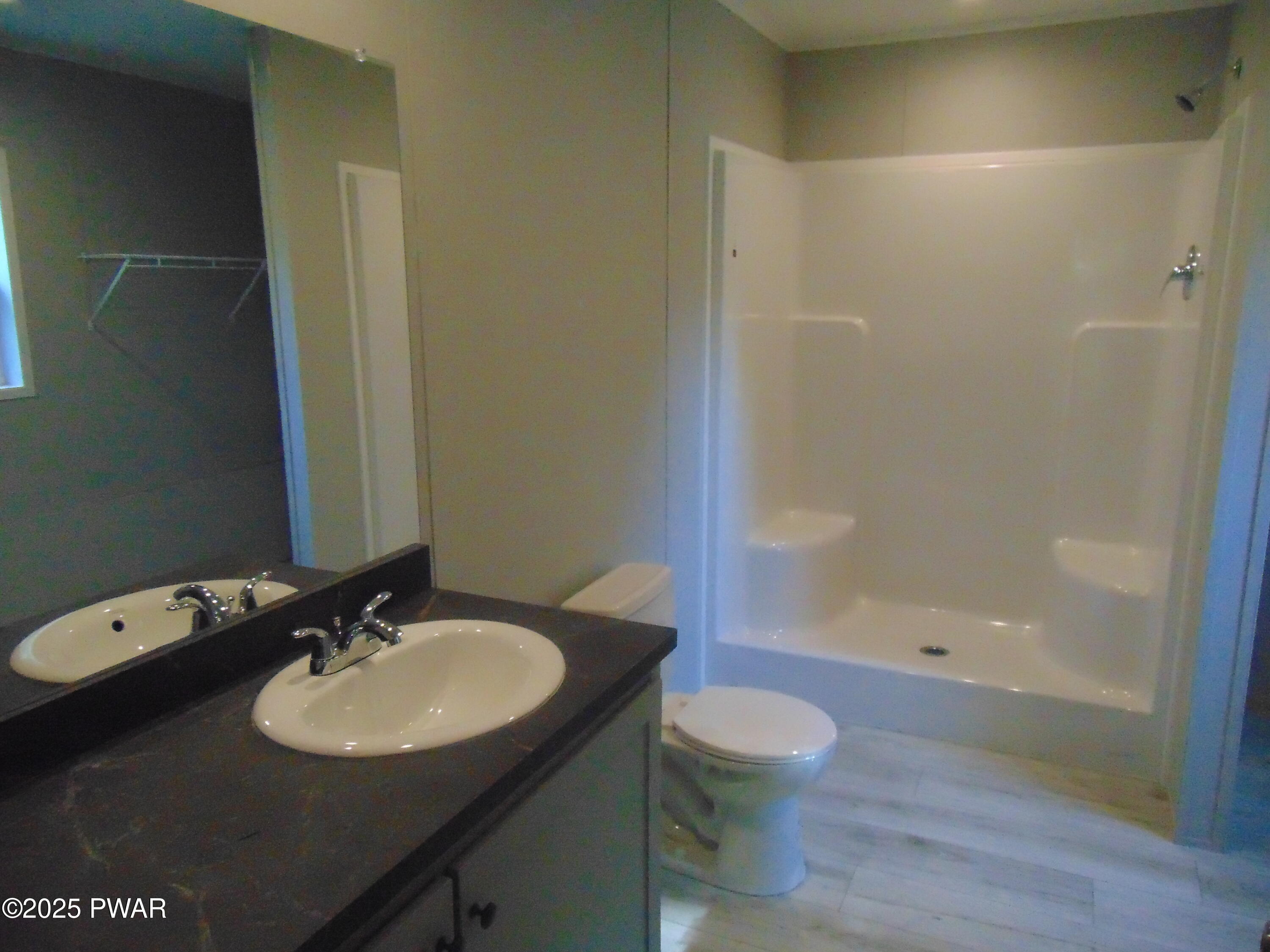 Bathroom with double-sink vanity, large mirror, toilet, and tub-shower combo.