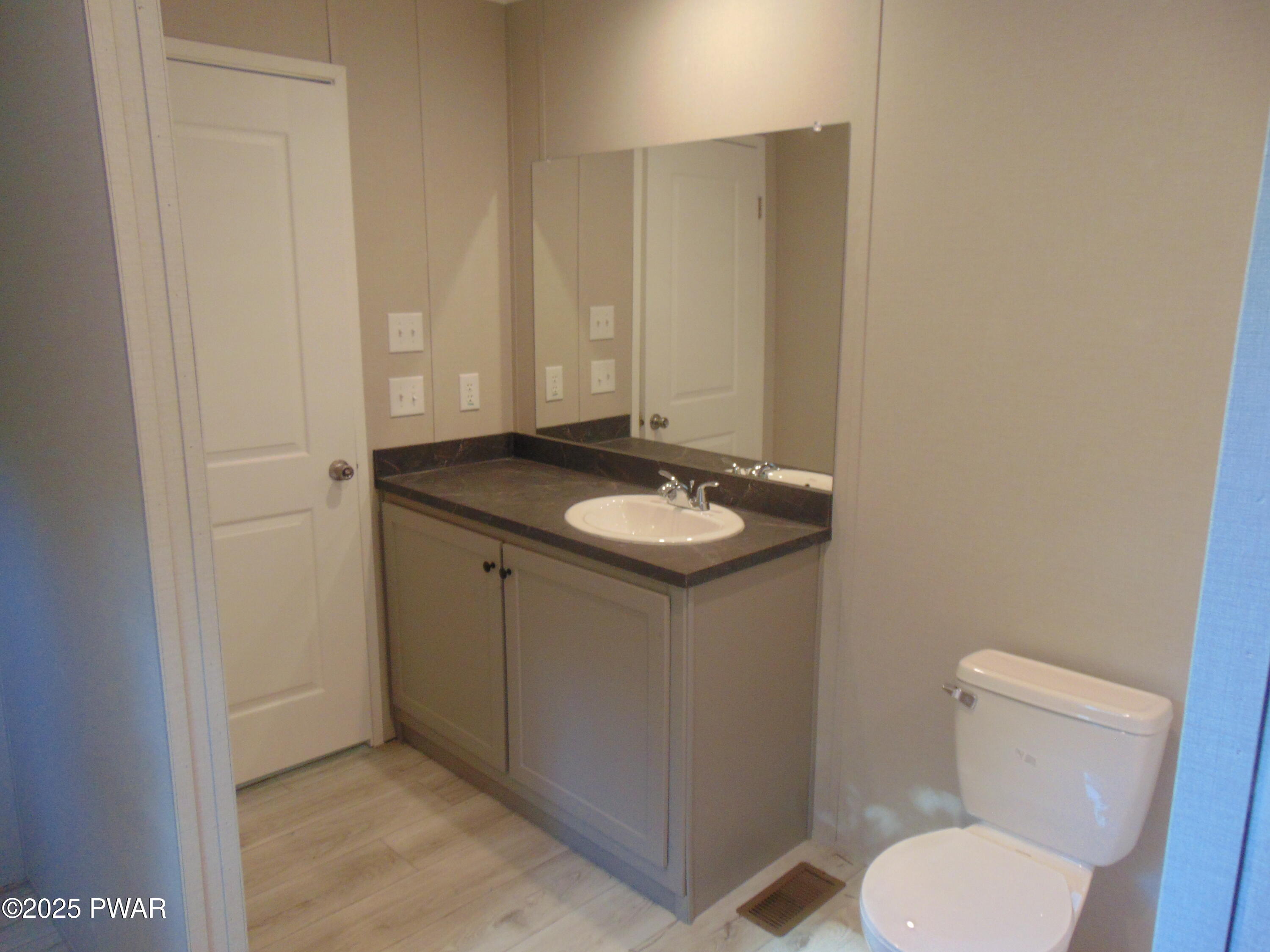 Bathroom with a single-sink vanity, large mirror, and toilet.