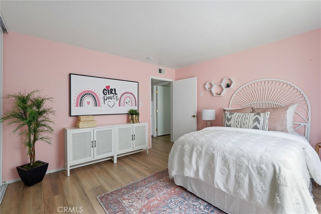 Pink bedroom at 372 Carroll E 201 with a white bed, matching dresser, potted plant, and patterned rug.