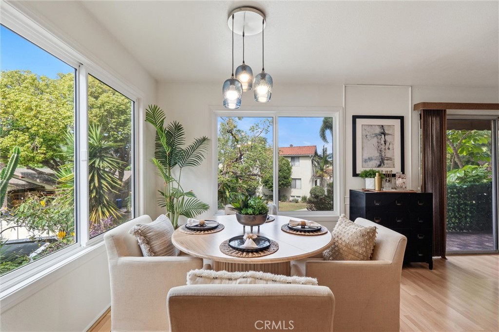 Bright dining area at 372 Carroll E 201 with a round table, upholstered chairs, pendant lights, and large windows overlooking greenery.