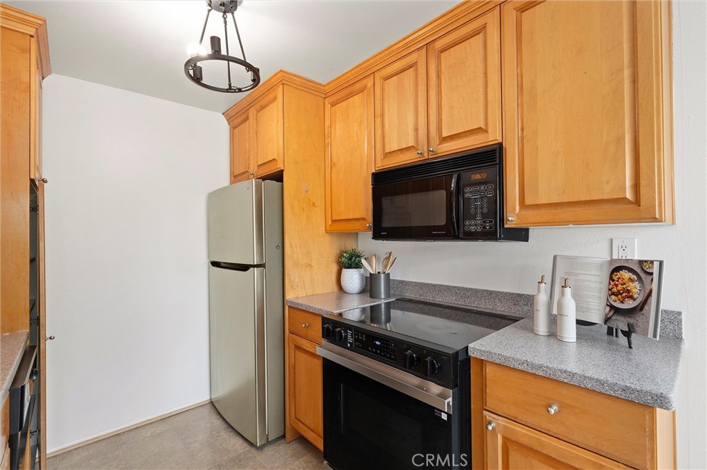 Kitchen at 372 Carroll E 201 with honey-colored wood cabinets, a stainless steel refrigerator, built-in microwave, electric range, and gray countertops.