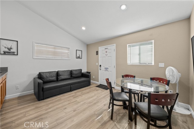A living room combined with a dining area featuring a black sofa and a glass-top dining table.