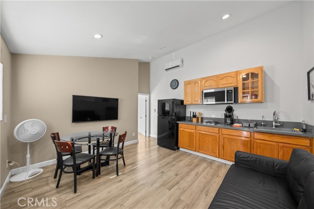 A furnished open-concept kitchen and living area with wood floors, wooden cabinets, and a dining table.
