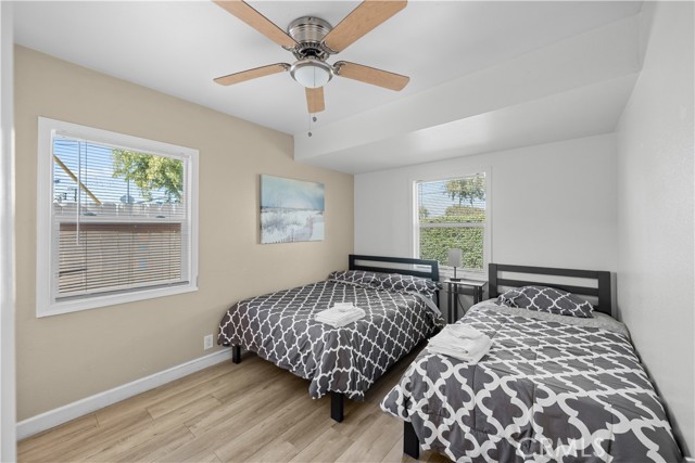 Bedroom with two beds, beige walls, and wood-look flooring
