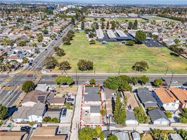 Aerial view showing a residential lot with a red boundary outline near a park and city street