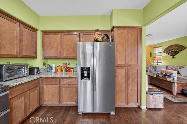 Kitchen with light wood cabinets, stainless steel appliances, and lime green walls, opening into a living room.