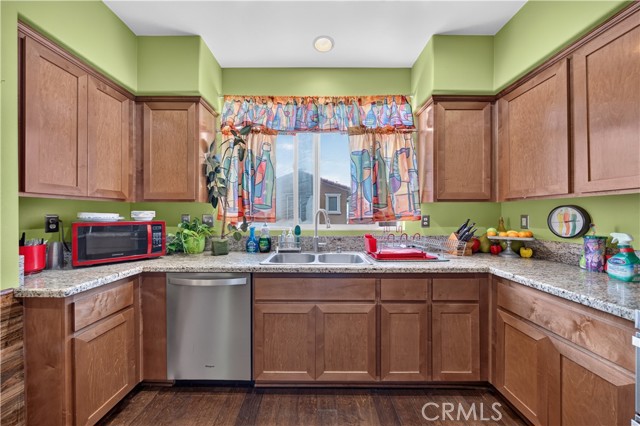 A kitchen with green walls, wood cabinets, and granite countertops.