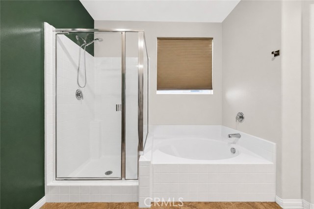A bathroom featuring a glass-enclosed shower stall next to a built-in tiled soaking tub with a window above it.
