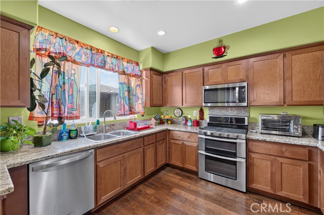 A kitchen with wooden cabinets, stainless steel appliances, and lime green walls.
