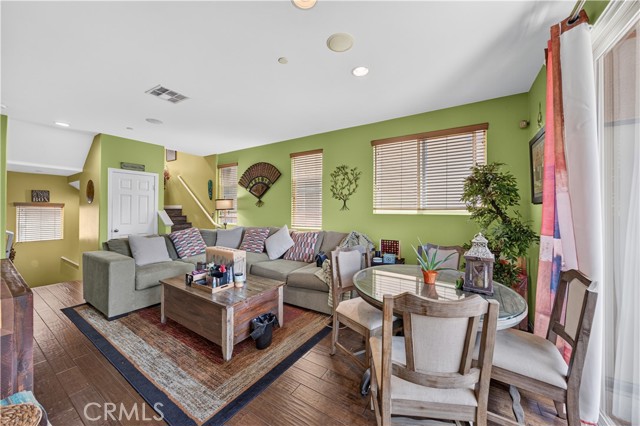 A furnished living room with light green walls, a large sectional sofa, and a glass-topped dining table.