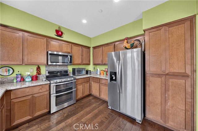 A kitchen with wooden cabinets, stainless steel appliances, and a light green wall.