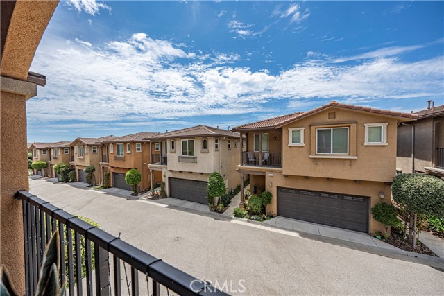 A view from an upper-level balcony overlooking a neighborhood of suburban townhouses on a sunny day