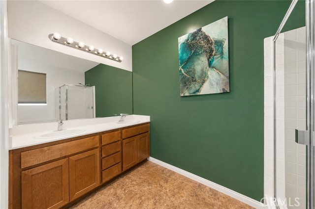 A bathroom featuring a wooden vanity, a large mirror, and a vibrant dark green accent wall with a modern abstract painting.