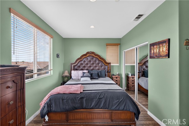 A bedroom with green walls, a dark wood tufted headboard, and a mirrored closet door