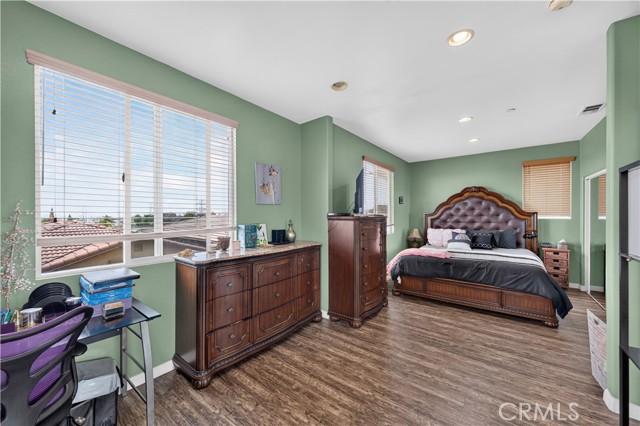 Spacious bedroom with green walls, dark wood furniture, and a king-sized bed.