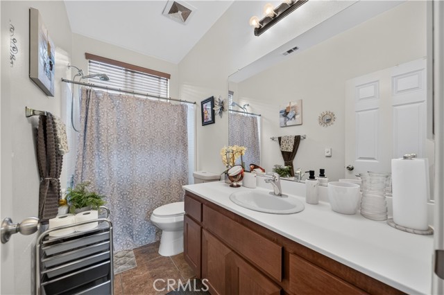 A clean, bright bathroom featuring a dark wood vanity with a white countertop, a shower curtain enclosing the tub area, and a large wall mirror.