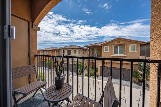A small balcony with a bistro set overlooking neighboring townhomes on a sunny day.