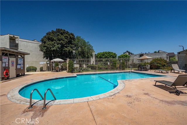 Community swimming pool with lounge chairs and residential building background