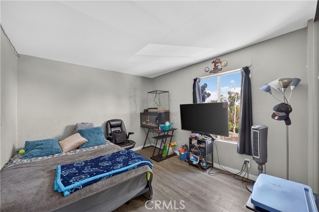 A bedroom with a bed, TV, and office chair in a lived-in state.