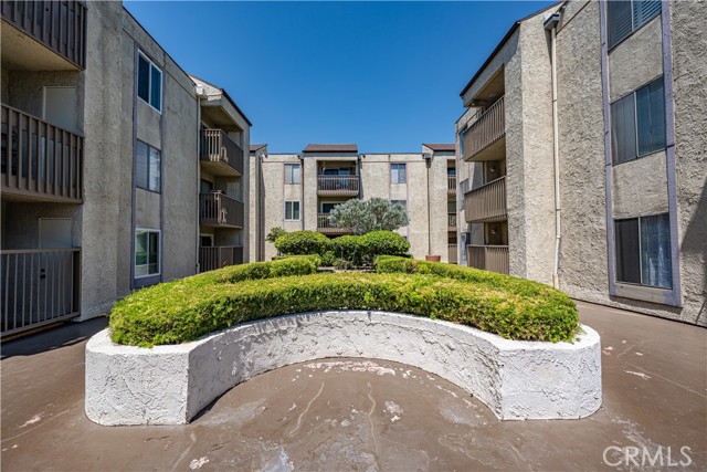 A central courtyard in an apartment complex with landscaped planters and surrounding multi-story building units.