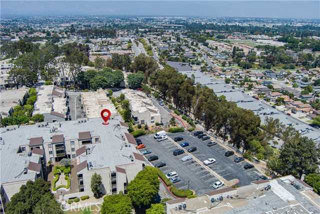 Aerial view of a residential apartment complex with a large parking lot and surrounding neighborhood