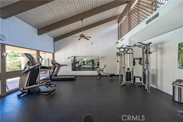 A spacious community gym with a vaulted ceiling, treadmill, elliptical, and weight machine.