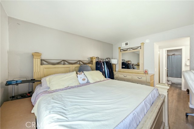 A bedroom with a king size bed and dresser, connected to an en-suite bathroom.