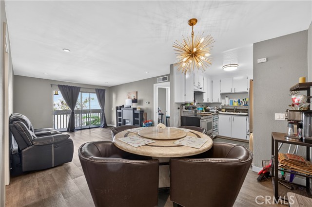 An open floor plan with a round dining table in the foreground, a kitchen to the right, and a living area with sliding glass doors in the background.