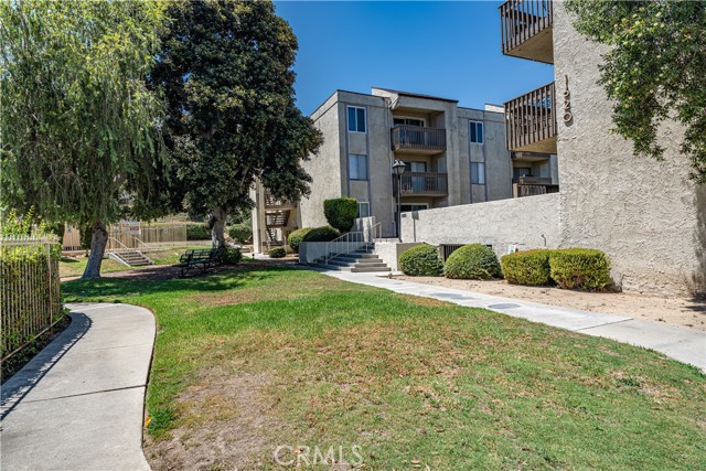 Exterior view of an apartment complex with lawn, sidewalk, and trees