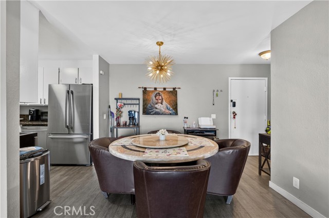 A dining room featuring a round table with four leather armchairs, a starburst chandelier, and a view into the adjacent kitchen.