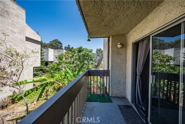 A wooden balcony overlooking a residential complex with lush green vegetation and trees.