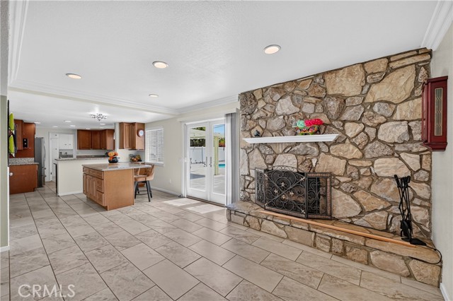Spacious living room with stone fireplace, tile floors, and open floor plan to kitchen