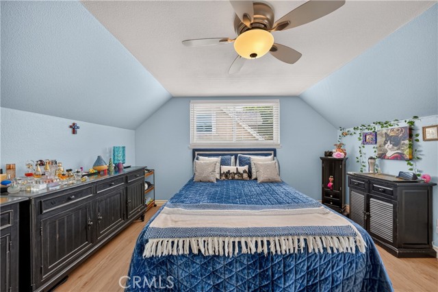 A bedroom with light blue walls, slanted ceilings, a blue quilt on the bed, and dark furniture.