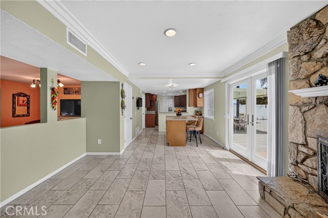 An open concept great room featuring tiled floors, a stone fireplace, and view into the kitchen