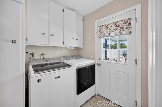 Laundry room with white washer and dryer, white cabinets above, and a door leading outside