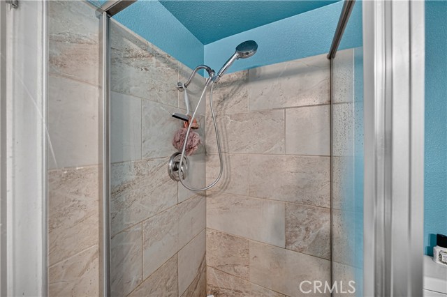 Close-up view of a tiled shower stall with a handheld showerhead and blue painted walls