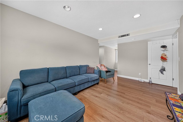 A living room with light grey walls, wood-look laminate flooring, and a large blue sectional sofa.