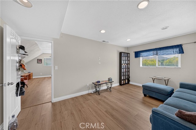 A living room with light wood flooring, a blue sofa, and a doorway leading to another room