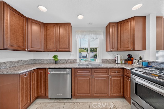A standard kitchen with wood cabinets, granite countertops, and stainless steel appliances