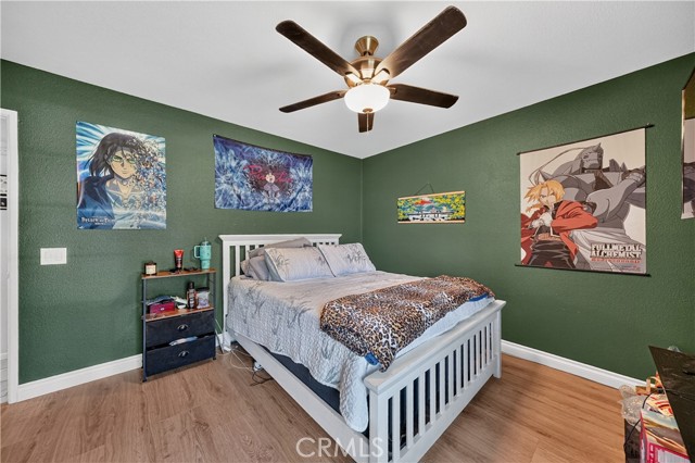 Bedroom with dark green walls, a white bed frame, and anime-themed wall decor.