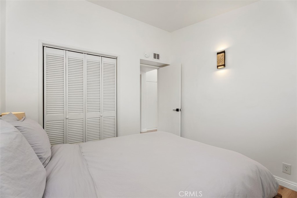 Bedroom at 9925 Rutland Avenue with a bed, white louvered closet doors, and an open doorway.
