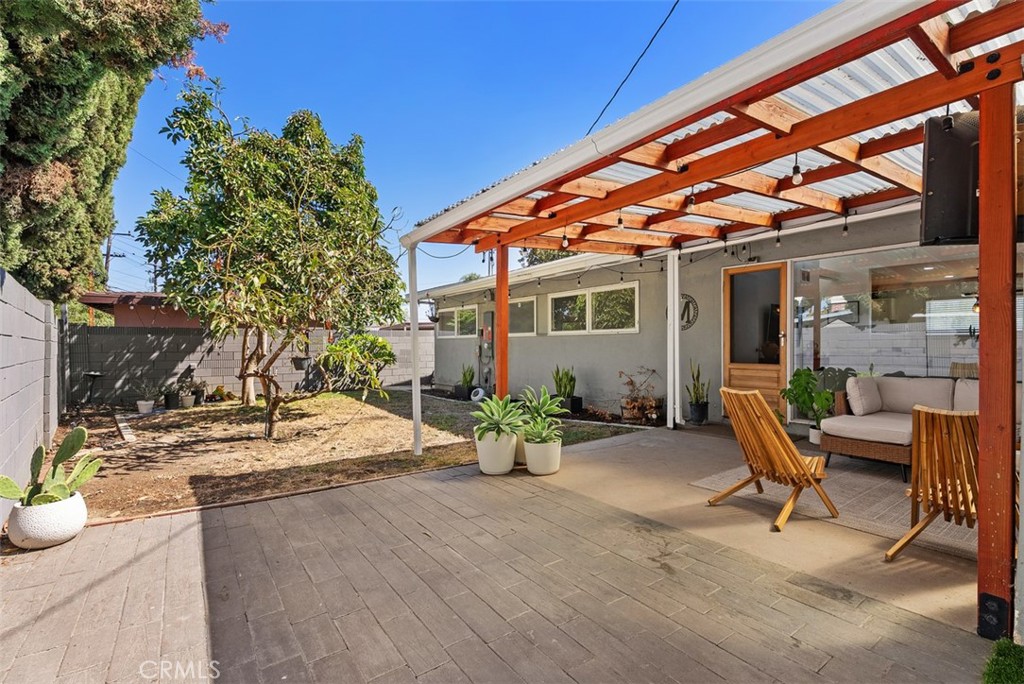 Covered patio with a timber pergola, outdoor dining chairs, and a seating area beside the home at 9925 Rutland Avenue